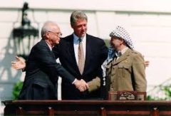 Yitzhak Rabin and Yasser Arafat shake hands in the presence of U.S. President Bill Clinton